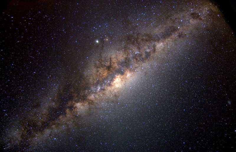 Die Milchstraße mit ihren wuchernden Staubwolken verläuft diagonal durchs Bild. Über der Mitte leuchten Jupiter und Antares, rechts am Rand steht die Kleine Magellansche Wolke.