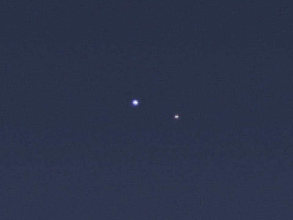 Zwei Lichtpunkte sind auf dem Bild zu sehen. Links ist die Erde, rechts der Mond. Das Bild wurde von der Raumsonde Cassini im Orbit um Saturn fotografiert.