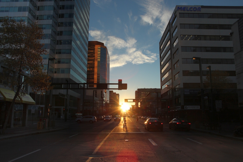 Am Ende einer Häuserschlucht aus Stahl und Glas geht die Sonne auf. Die Straße ist die Jasper Avenue in Edmonton im kanadischen Alberta. 